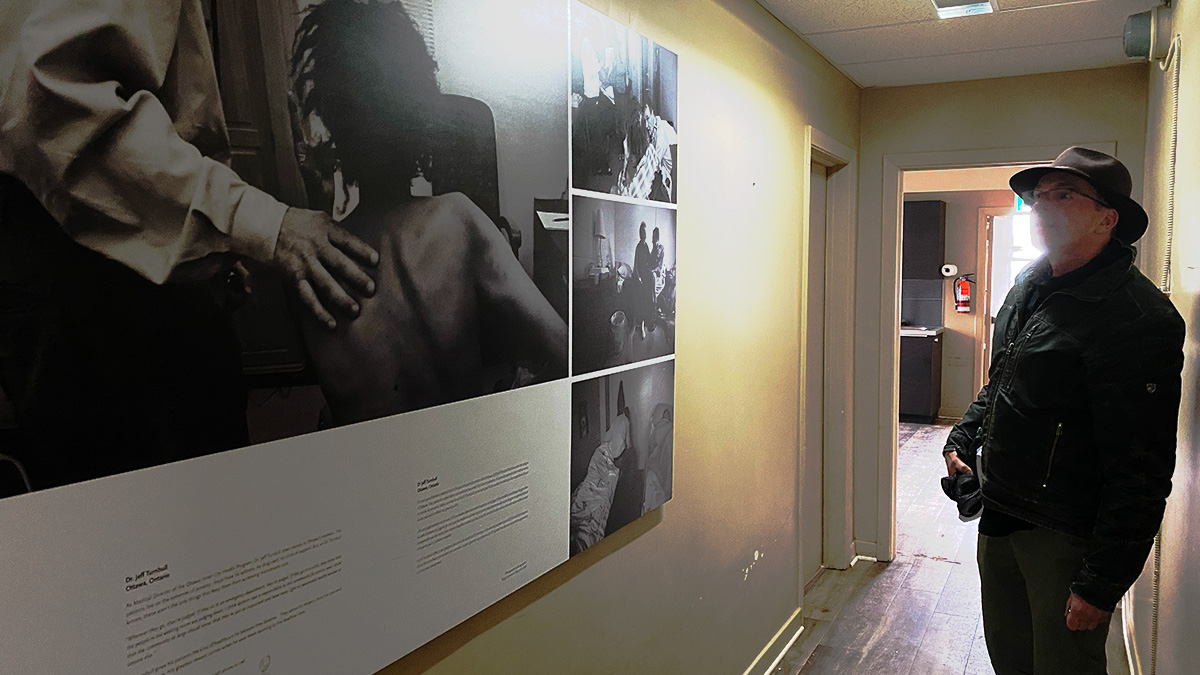 Rob Boyd stands in Ottawa Inner City Health's old location in front of a display of photos by Montreal-based photographer Roger Lemoyne. The piece, "Inner City Health program, Ottawa" is part of Lemoyne's Canadiana collection. The images capture the focus of Ottawa Inner City Health: providing healthcare, community connections and harm reduction supports to people who use drugs.